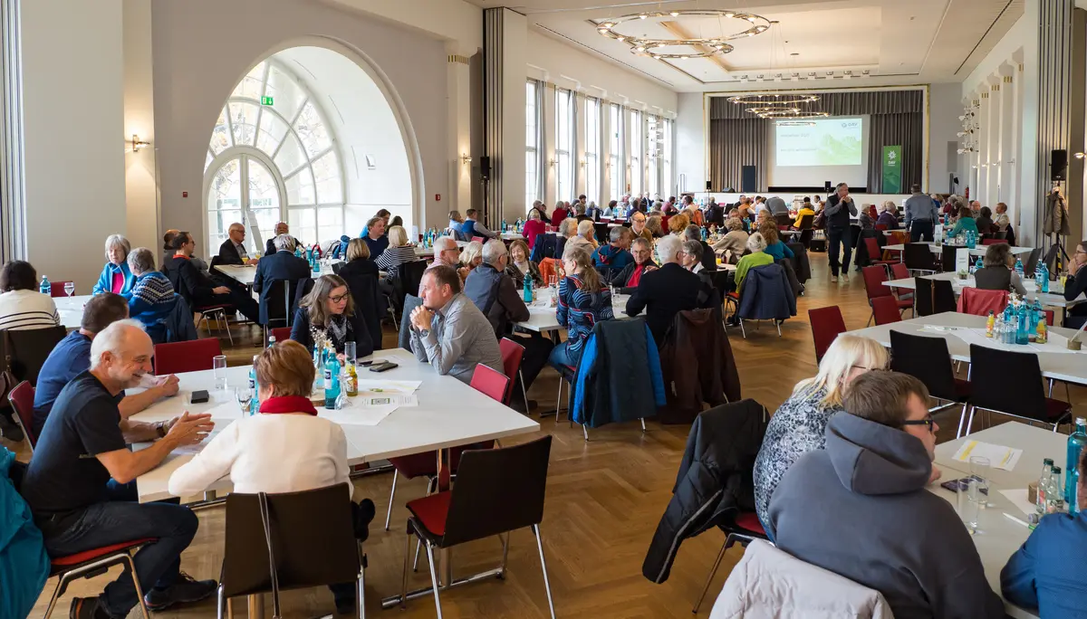 Viele Menschen sitzen an Tischen und unterhalten sich im Kursaal Bad Cannstatt. | © Mick Murphy