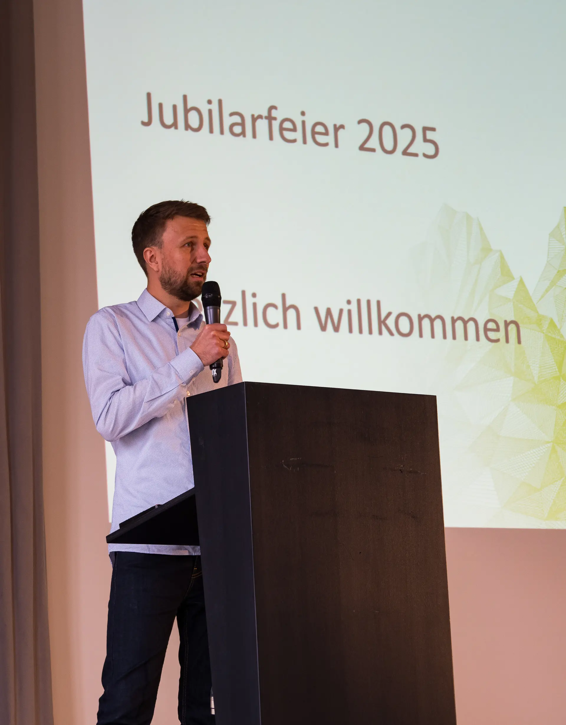 Felix Winkler, ein junger Mann, begrüßt die Menschen mit dem Mikrofon. | © Mick Murphy