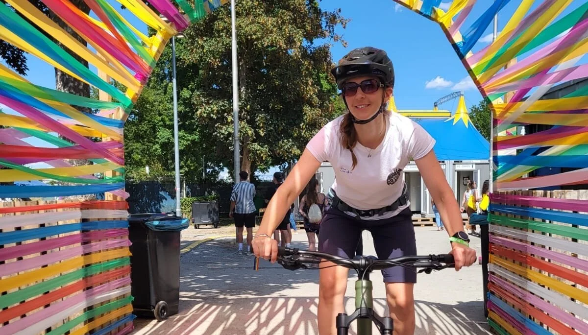 Frau fährt auf dem Mountainbike unter einem Boden aus Farbbändern durch | © Gabriel Molitor