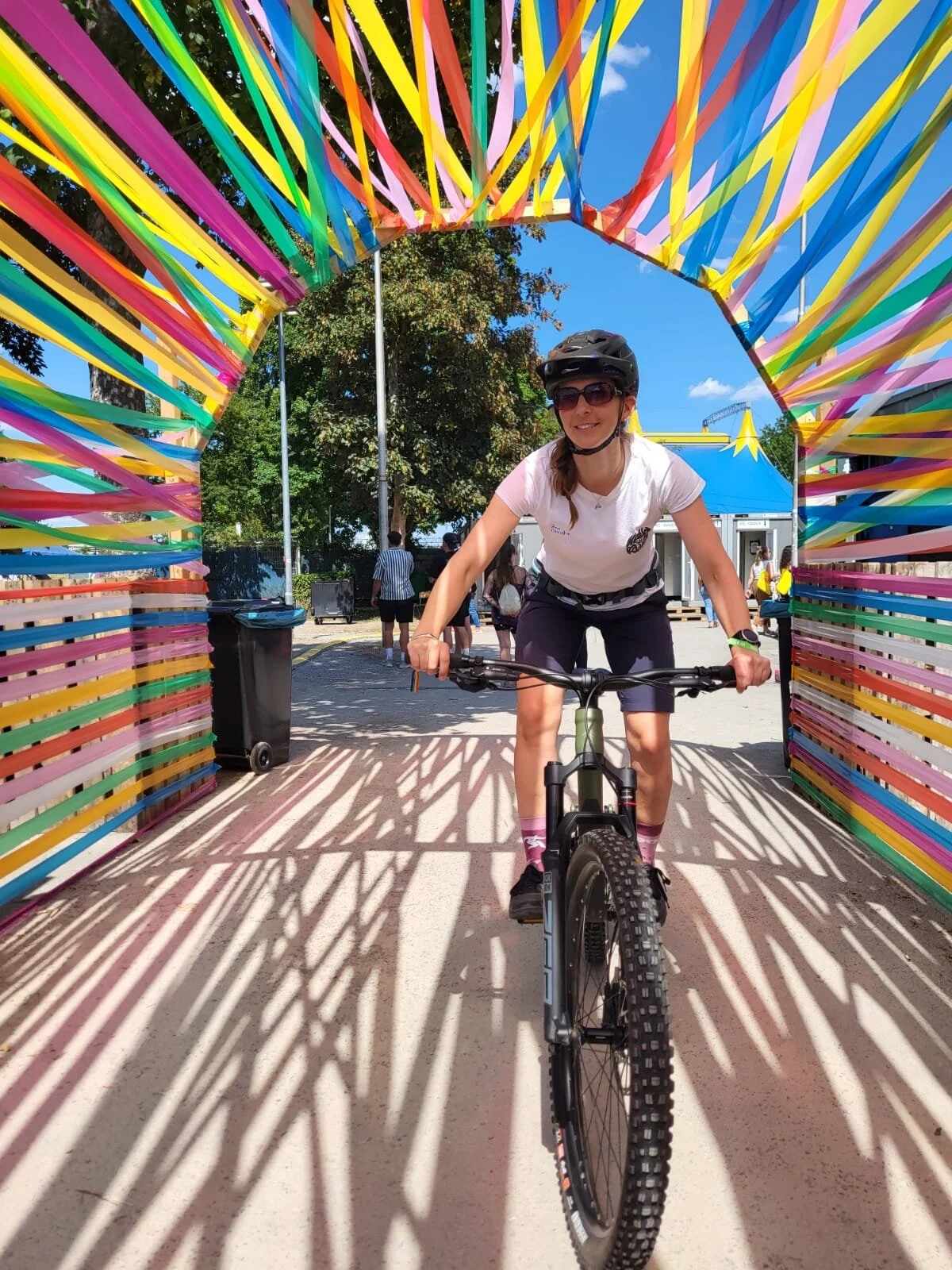 Frau fährt auf dem Mountainbike unter einem Boden aus Farbbändern durch | © Gabriel Molitor
