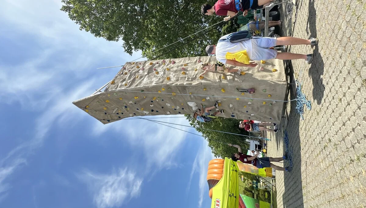 Junger Mann erklärt Vater etwas, während das Kind am Kletterturm klettert | © Sandra Holt