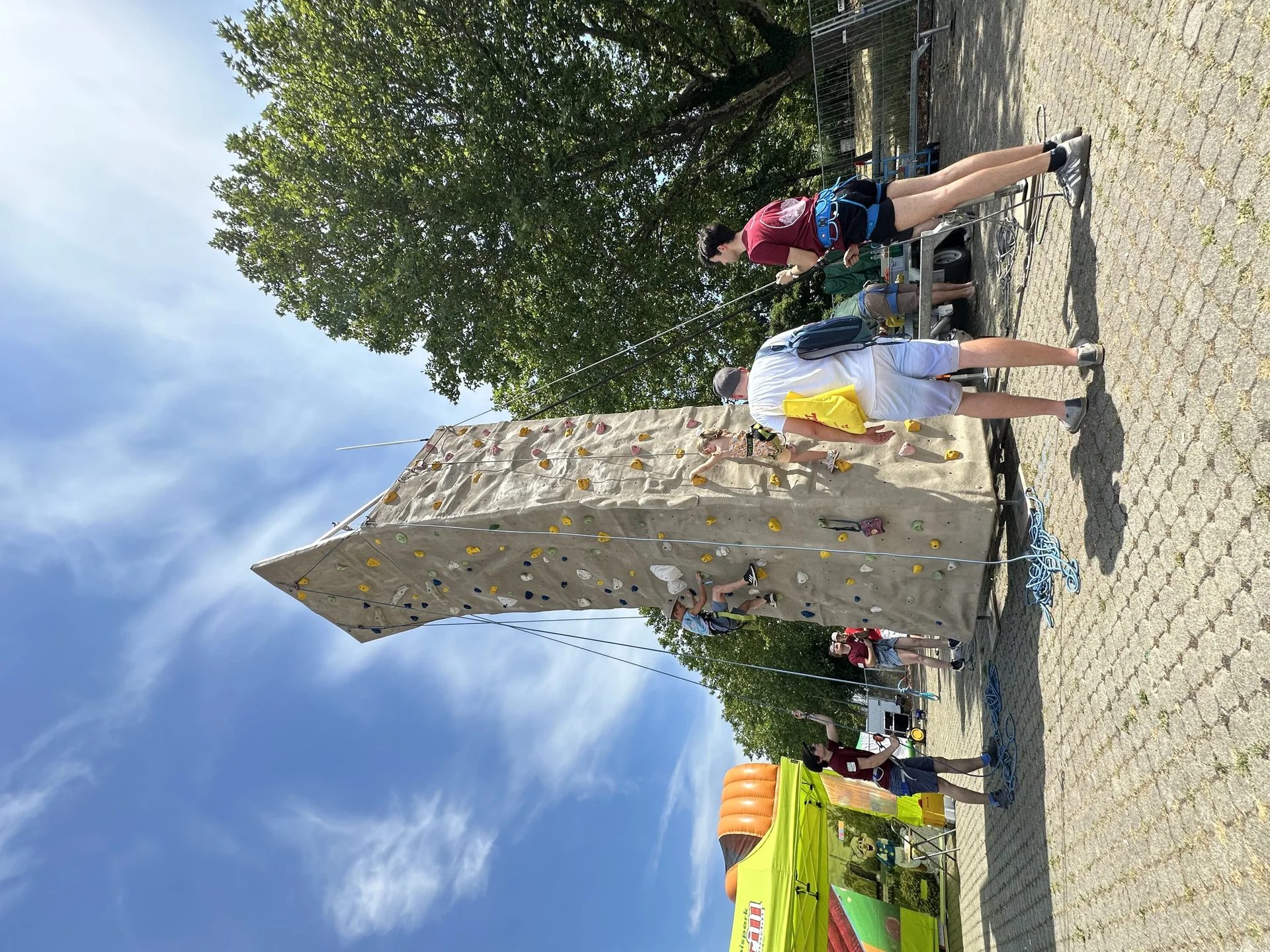 Junger Mann erklärt Vater etwas, während das Kind am Kletterturm klettert | © Sandra Holt