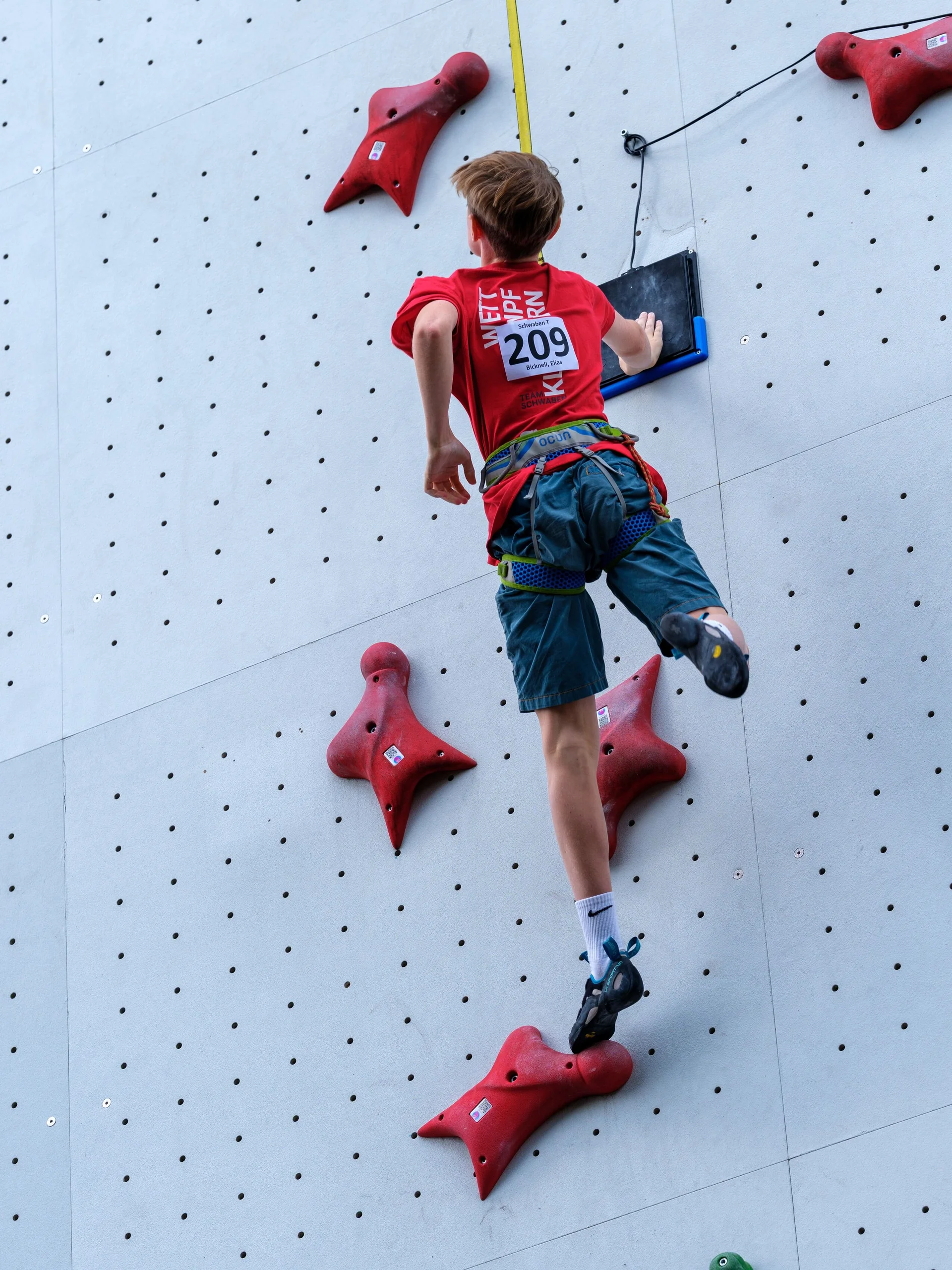 Kletternder Jugendlicher an einer Kletterwand nach dem Abklatschen am Ziel | © Oliver Gobin