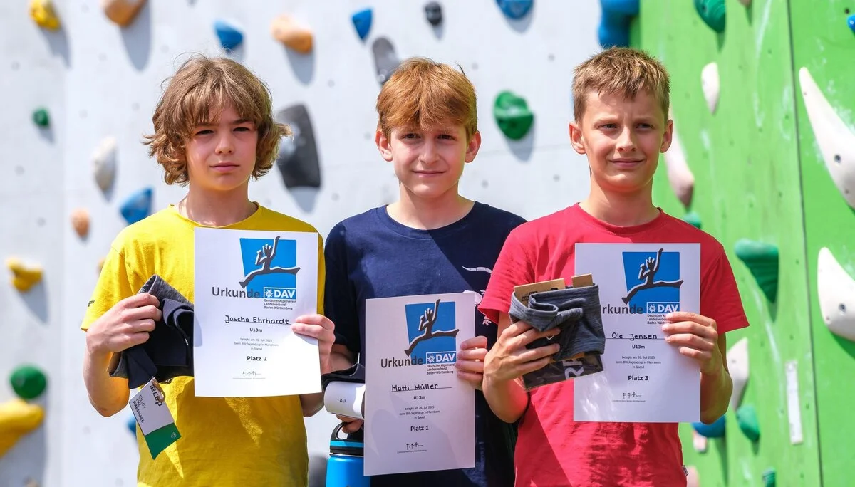 Siegerehrung dreier Jungen vor einer Kletterwand | © Oliver Gobin
