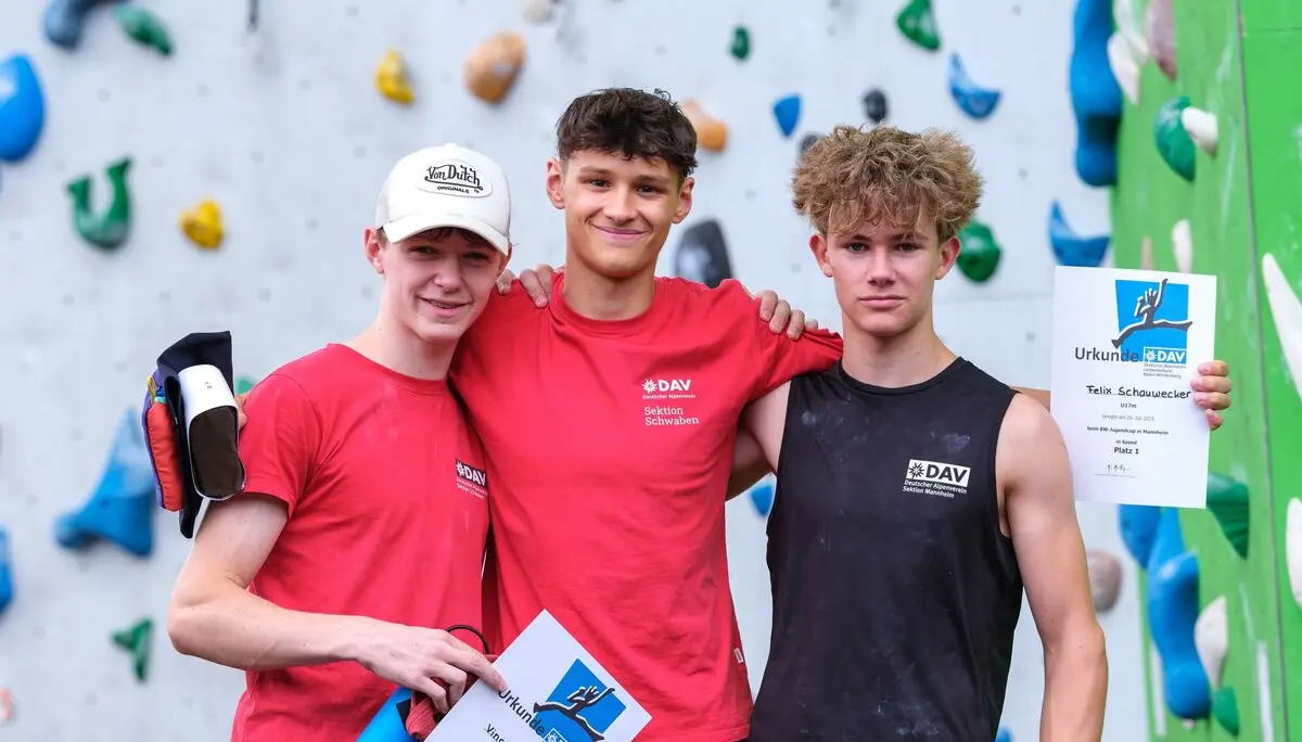 Siegerehrung dreier Jugendlicher vor einer Kletterwand | © Oliver Gobin