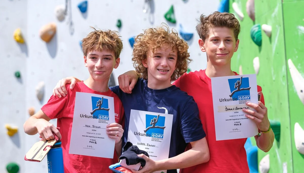 Siegerehrung dreier Jungen vor einer Kletterwand | © Oliver Gobin