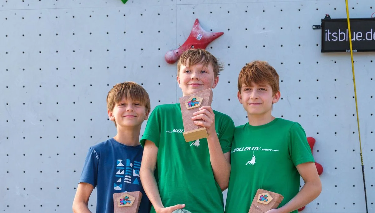Drei Jungen mit Pokalen auf einem Podest | © @oliverclimb / Oliver Gobin
