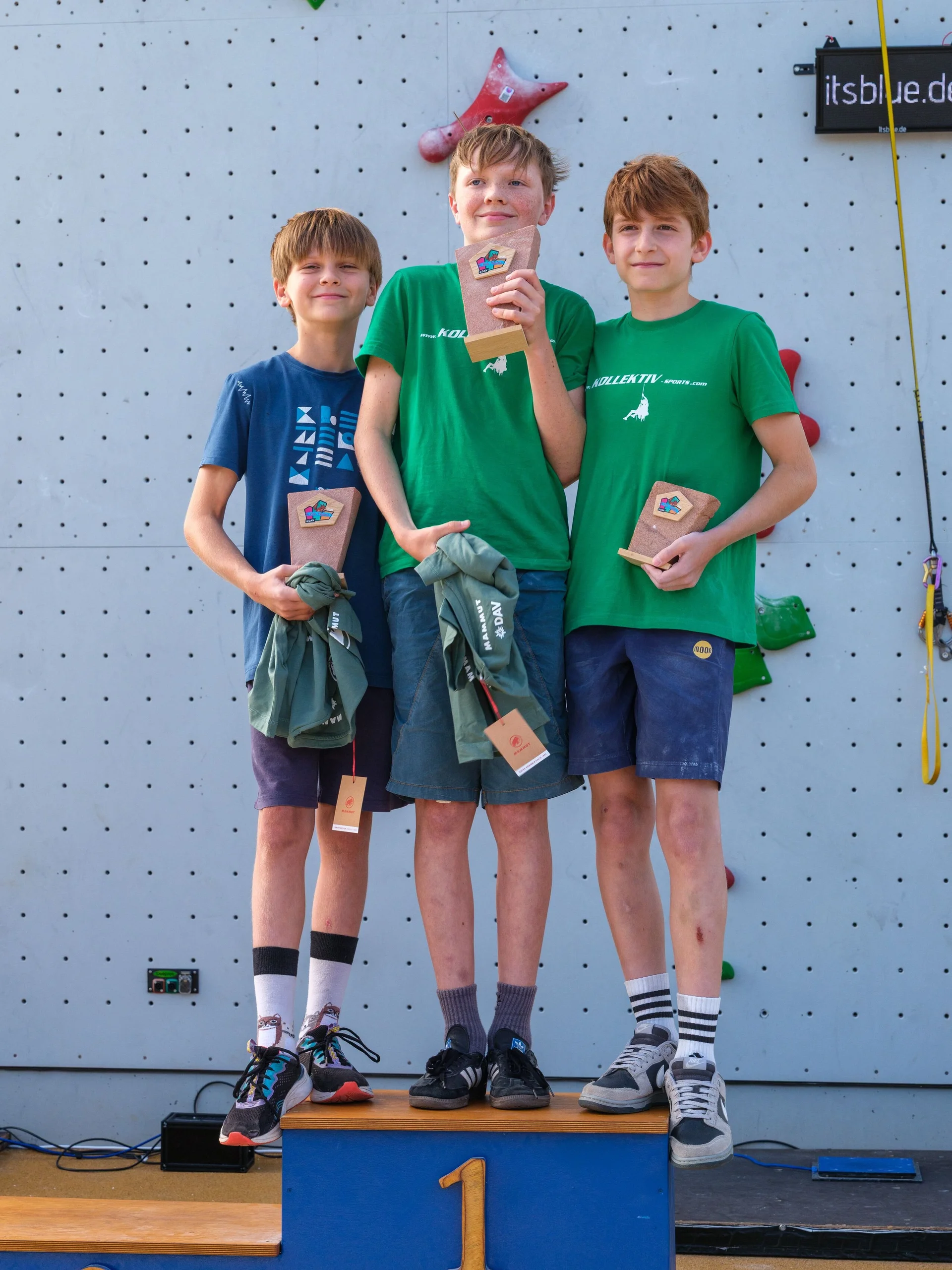Drei Jungen mit Pokalen auf einem Podest | © @oliverclimb / Oliver Gobin