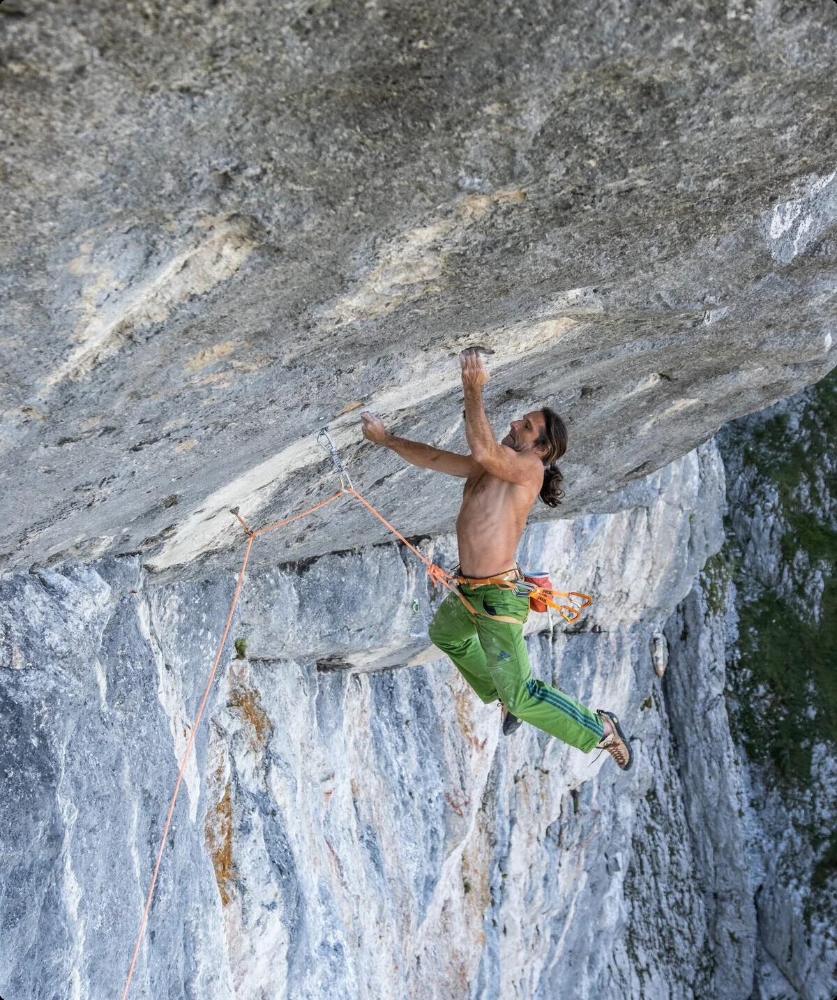 Mann klettert oberkörperfrei in einem Überhang am Fels | © Alexander Huber