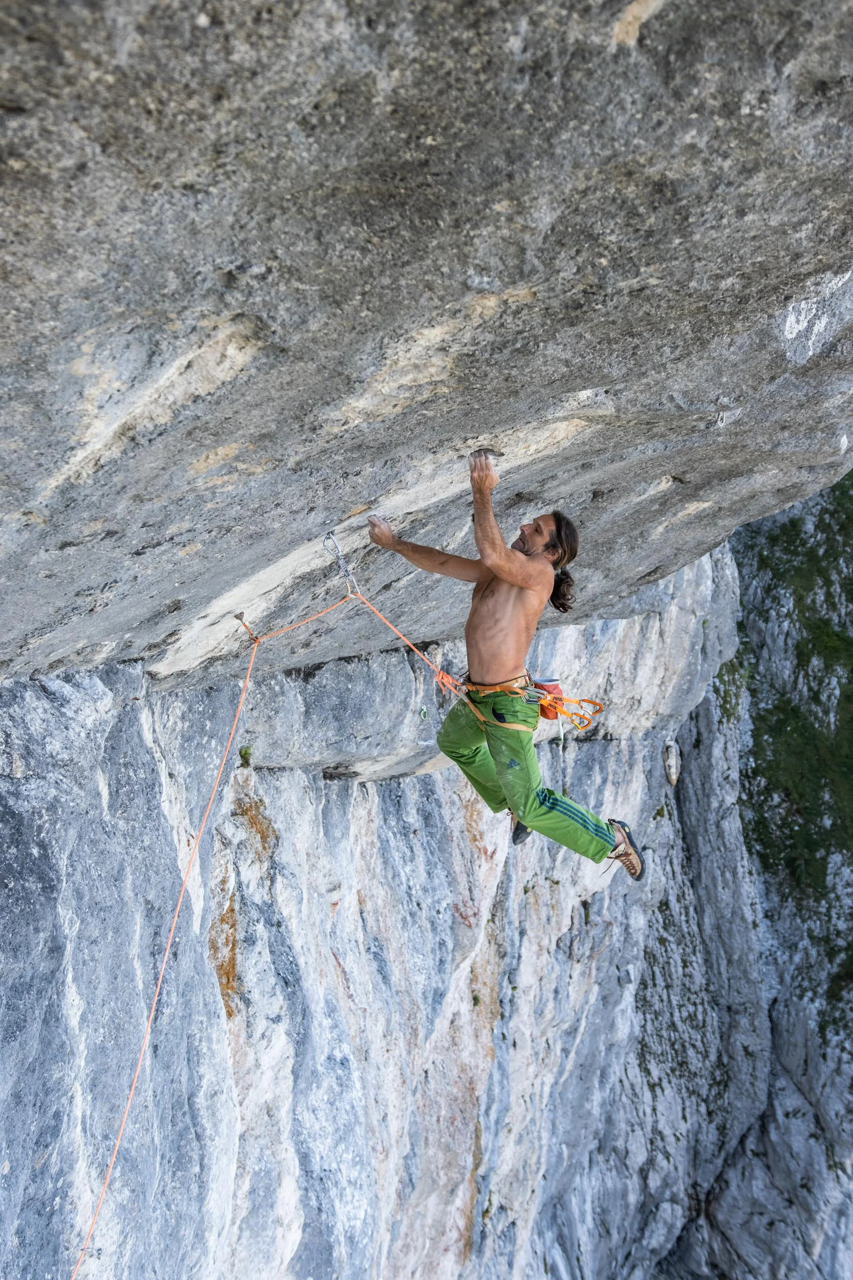 Mann klettert oberkörperfrei in einem Überhang am Fels | © Alexander Huber