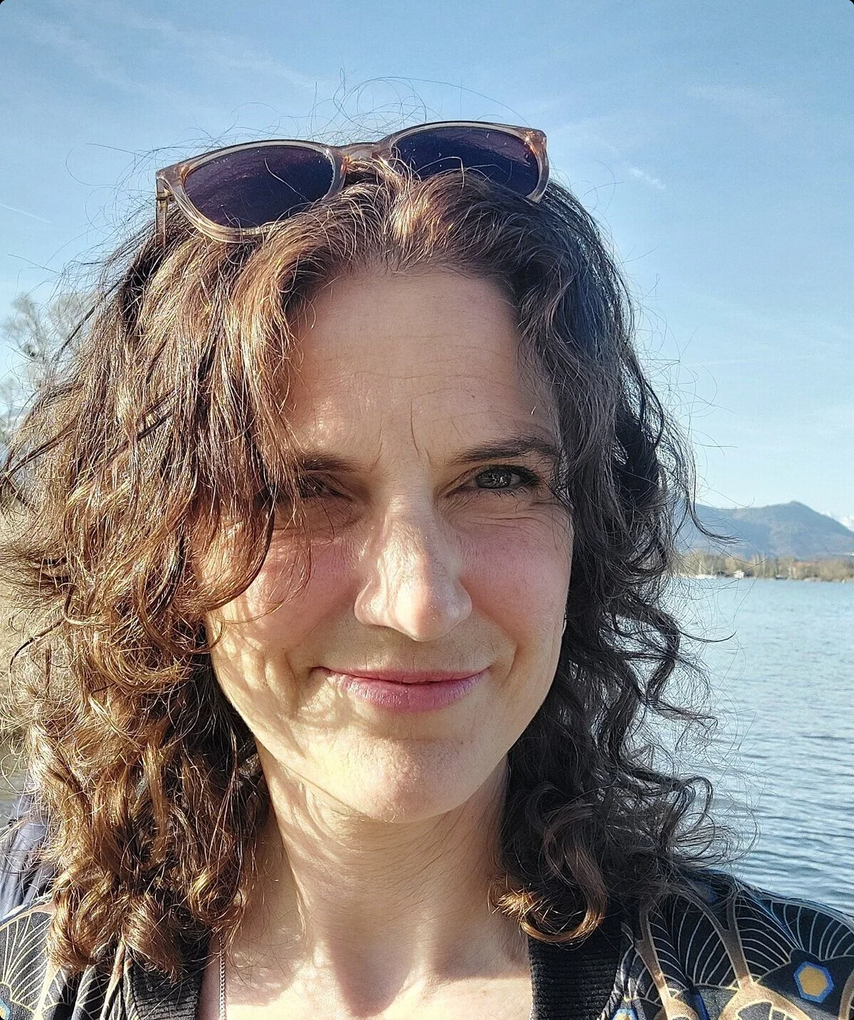 Portrait einer Frau mit dunklen Haaren, die ihre Sonnenbrille ins Haar gesteckt hat | © Stefanie Pausch