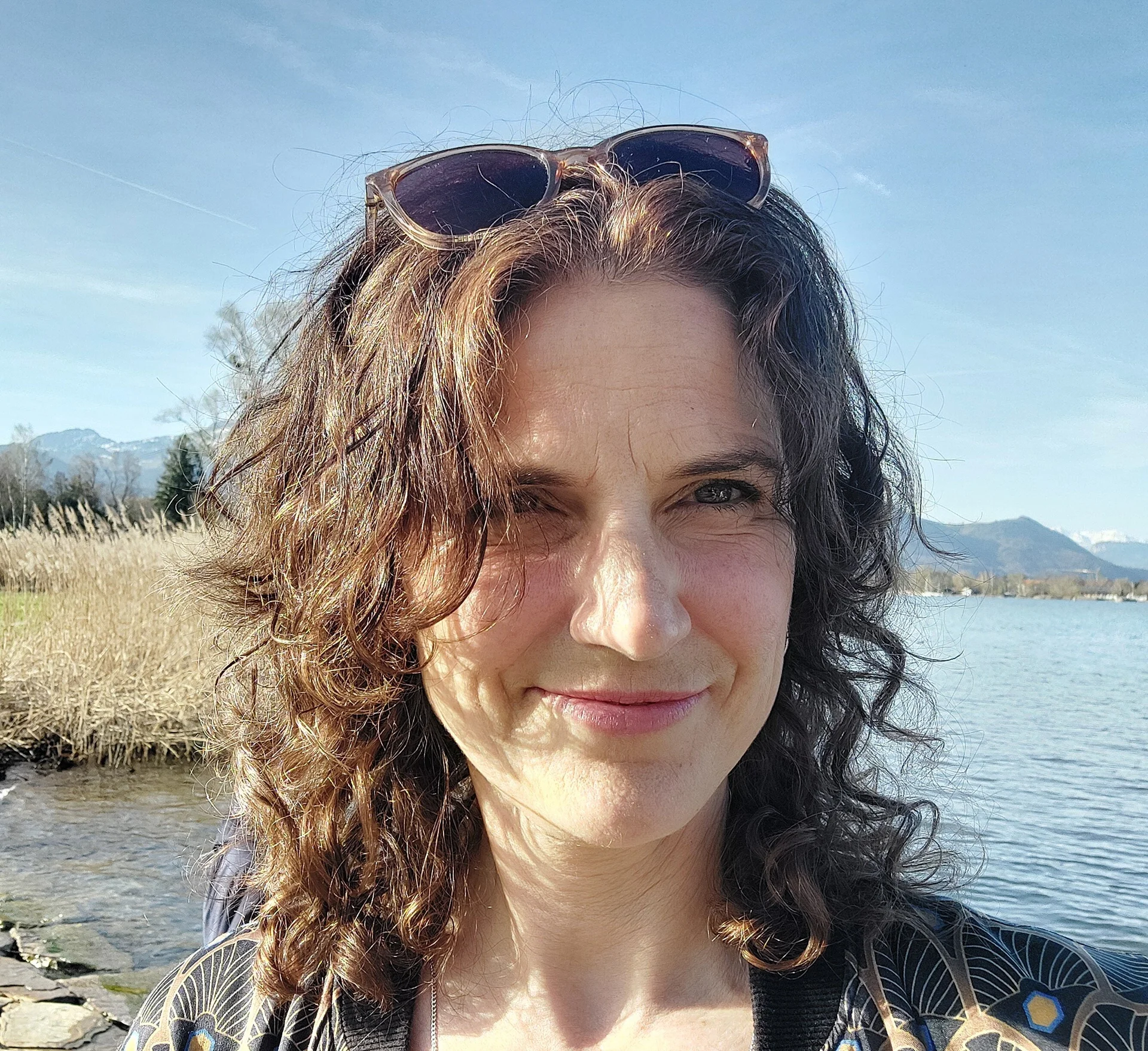 Portrait einer Frau mit dunklen Haaren, die ihre Sonnenbrille ins Haar gesteckt hat | © Stefanie Pausch