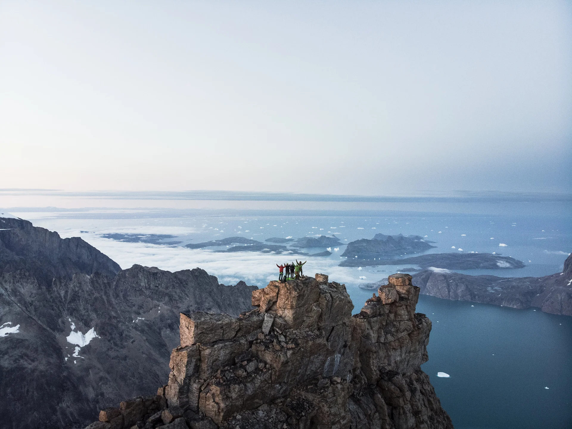 Gruppe von Kletterern steht auf Fels umgeben von einem Bergpanorama | © © Stefan Glowacz GmbH