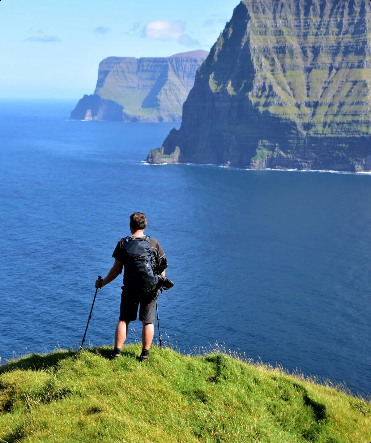 Mann steht auf Klippe und blickt gen Meer. Im Hintergrund ragen begrünte Felsen aus dem Wasser. | © Verena Schmidt