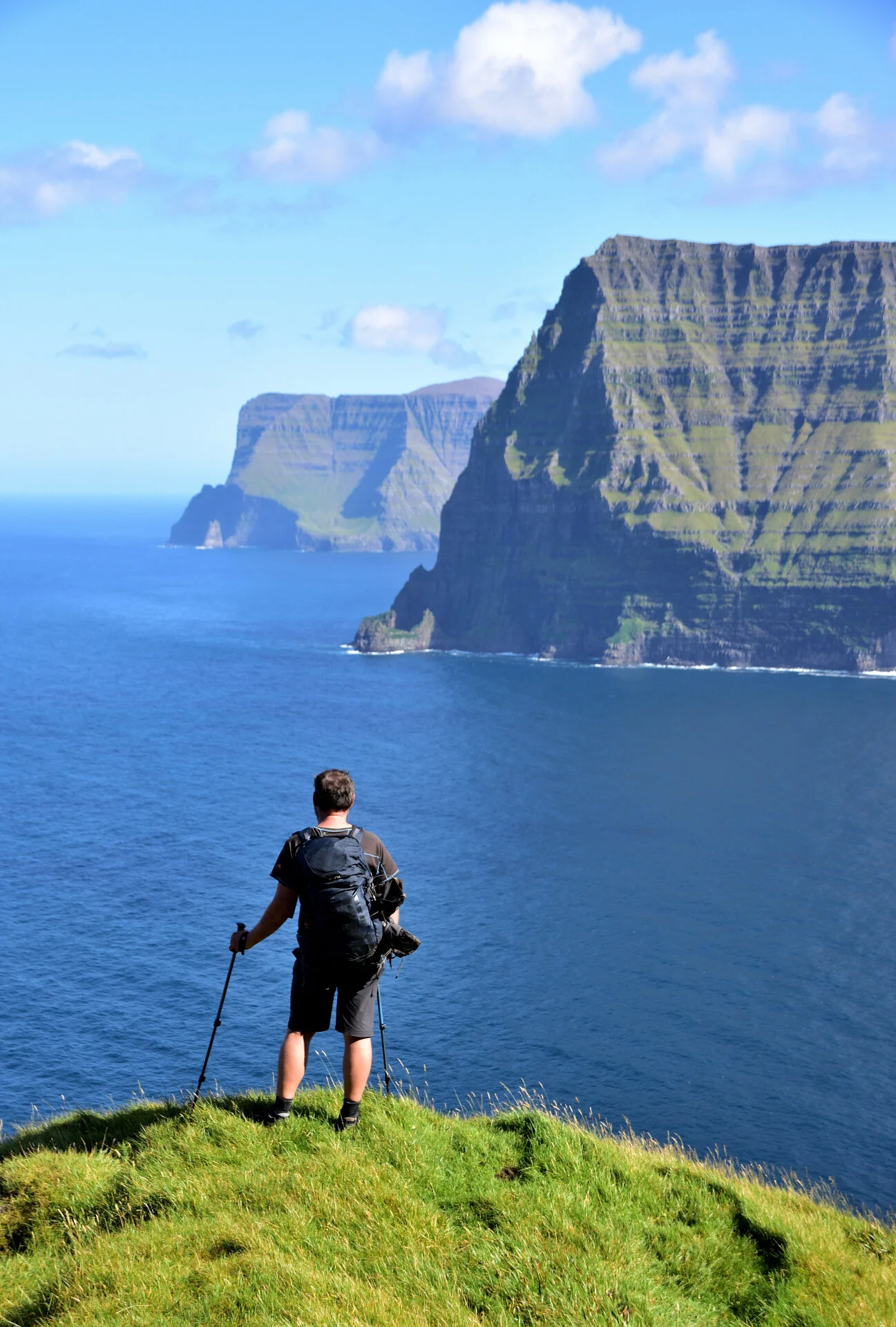 Mann steht auf Klippe und blickt gen Meer. Im Hintergrund ragen begrünte Felsen aus dem Wasser. | © Verena Schmidt