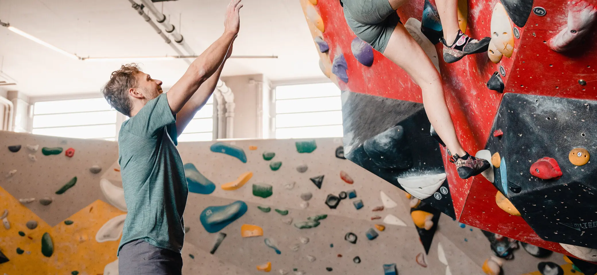 Eine Frau klettert in einer Kletterhalle, ihr Partner sichert sie. | © DAV/Marisa Koch