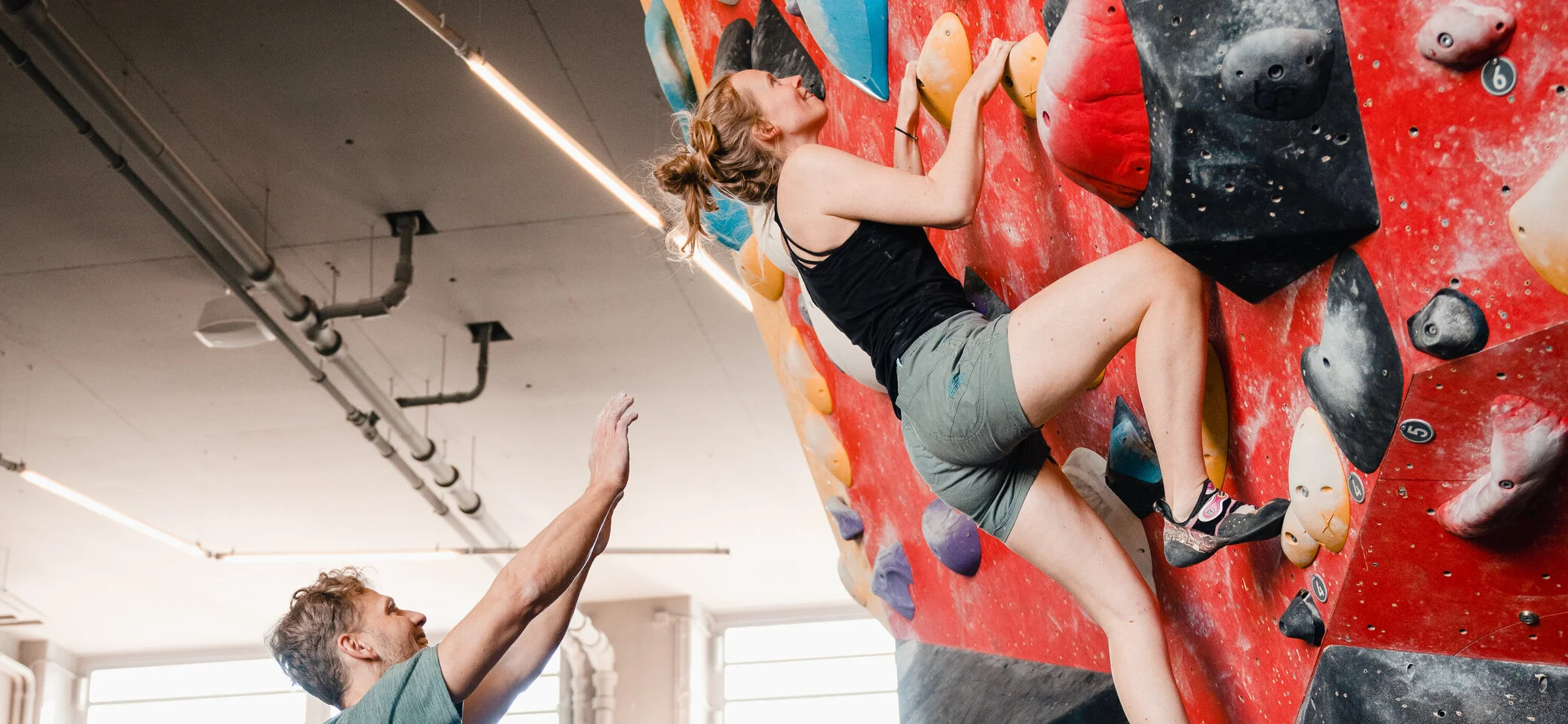 Eine Frau klettert in einer Kletterhalle, ihr Partner sichert sie. | © DAV/Marisa Koch