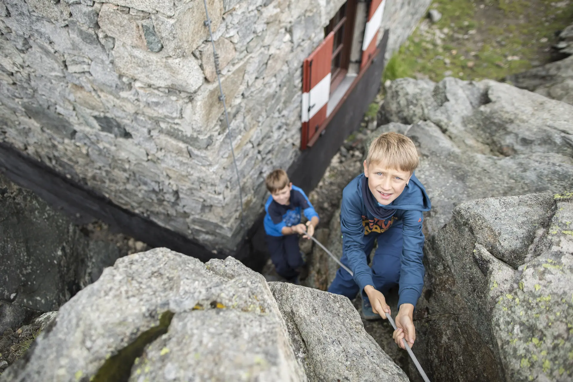 Ein Junge übt Klettern am Felsen und wird von unten gesichert | © DAV / Jens Klatt